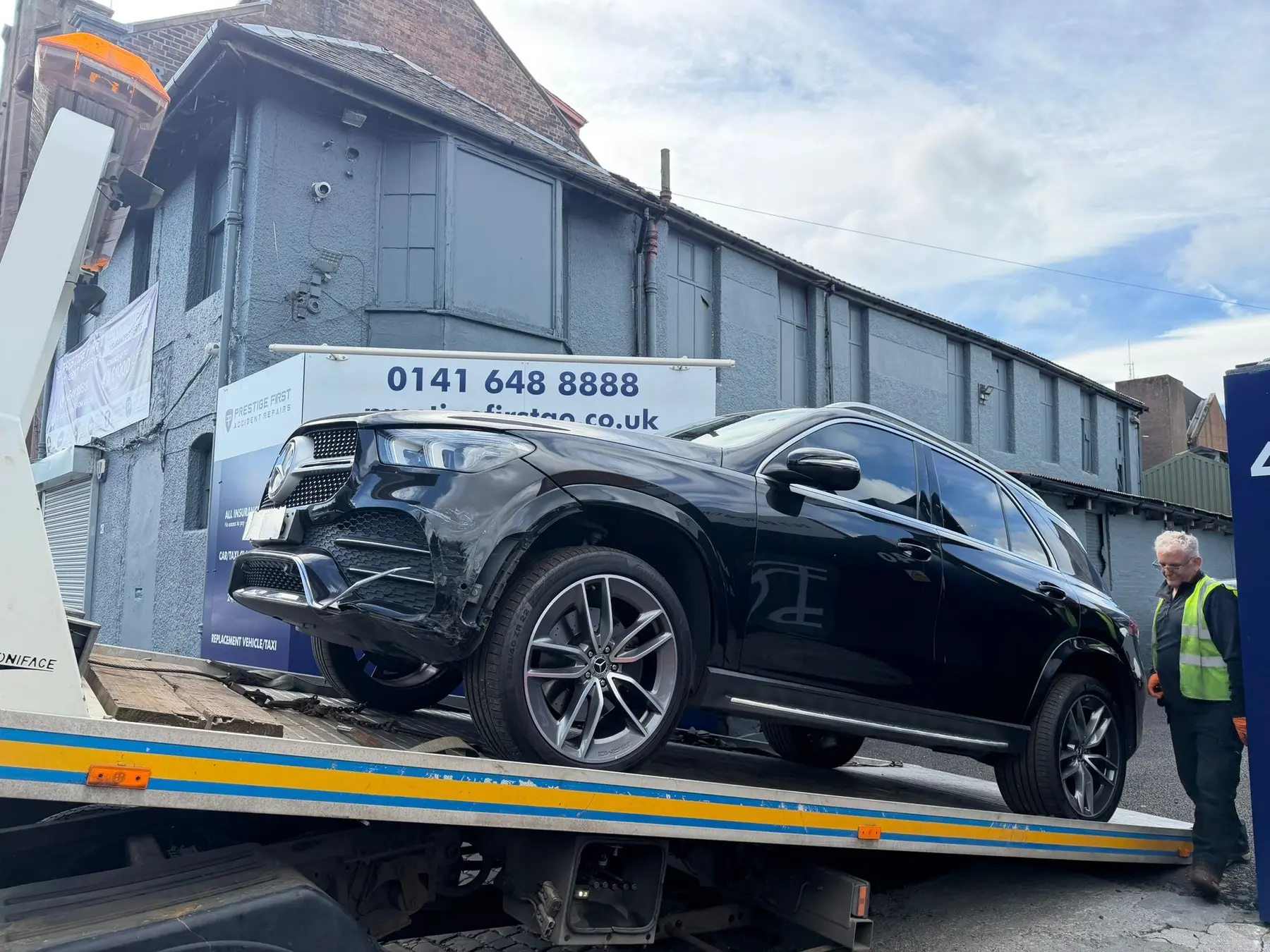 Accident damaged Mercedes on a recovery vehicle outside Prestige First in Glasgow