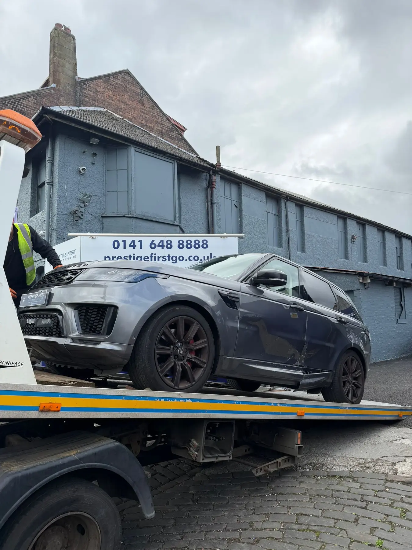 Damaged grey Range Rover on a recovery truck at Prestige First Glasgow